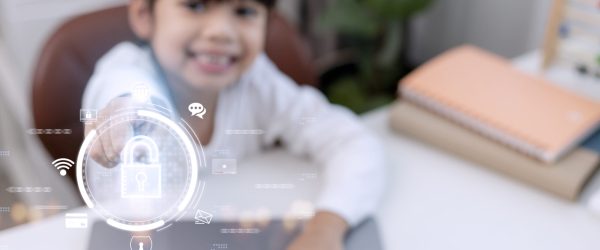 Child safety online. Little girl using laptop at home. icon of internet blocking app on foreground