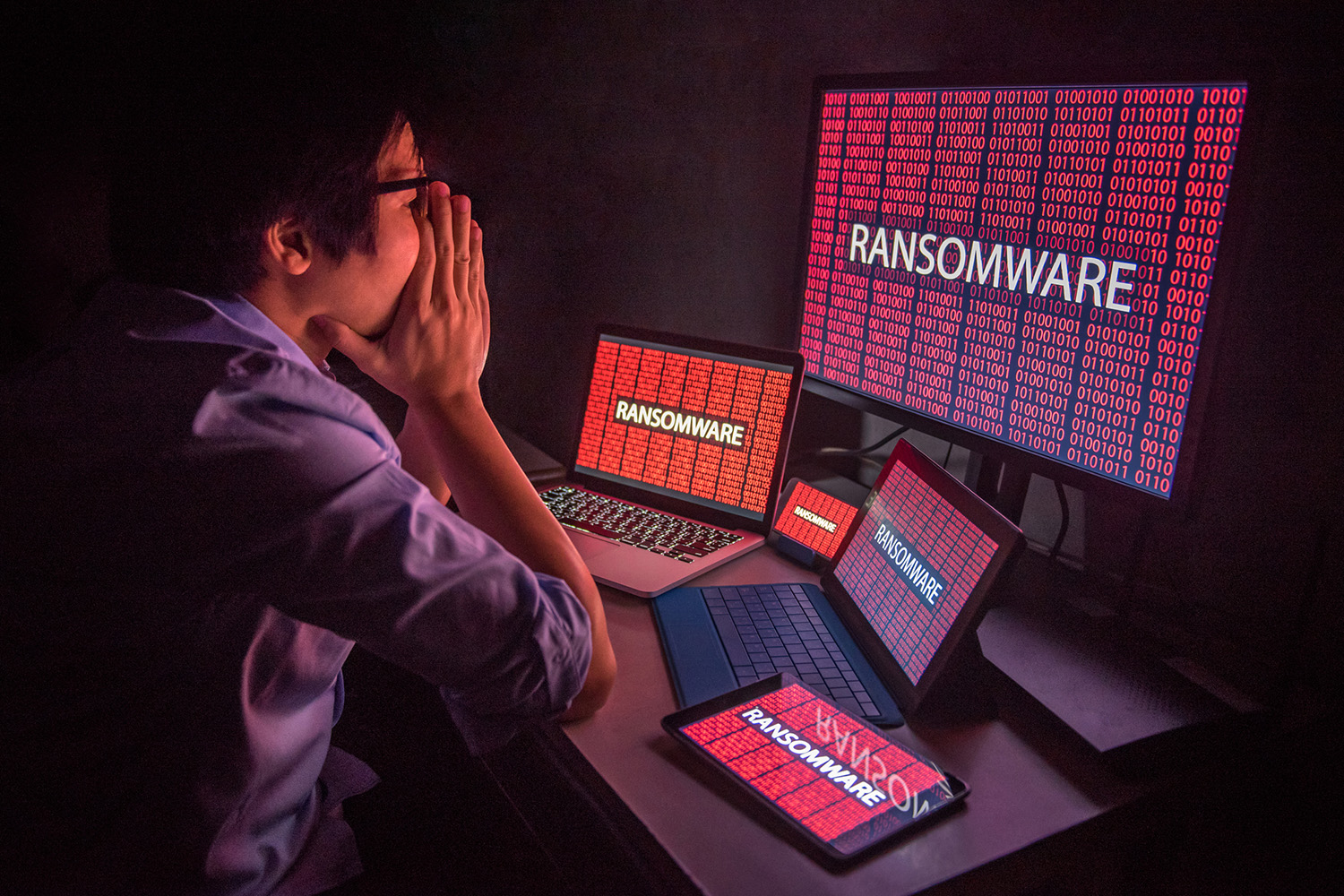 Young Asian male frustrated, confused and headache by ransomware attack on desktop screen, notebook and smartphone, cyber attack and internet security concepts