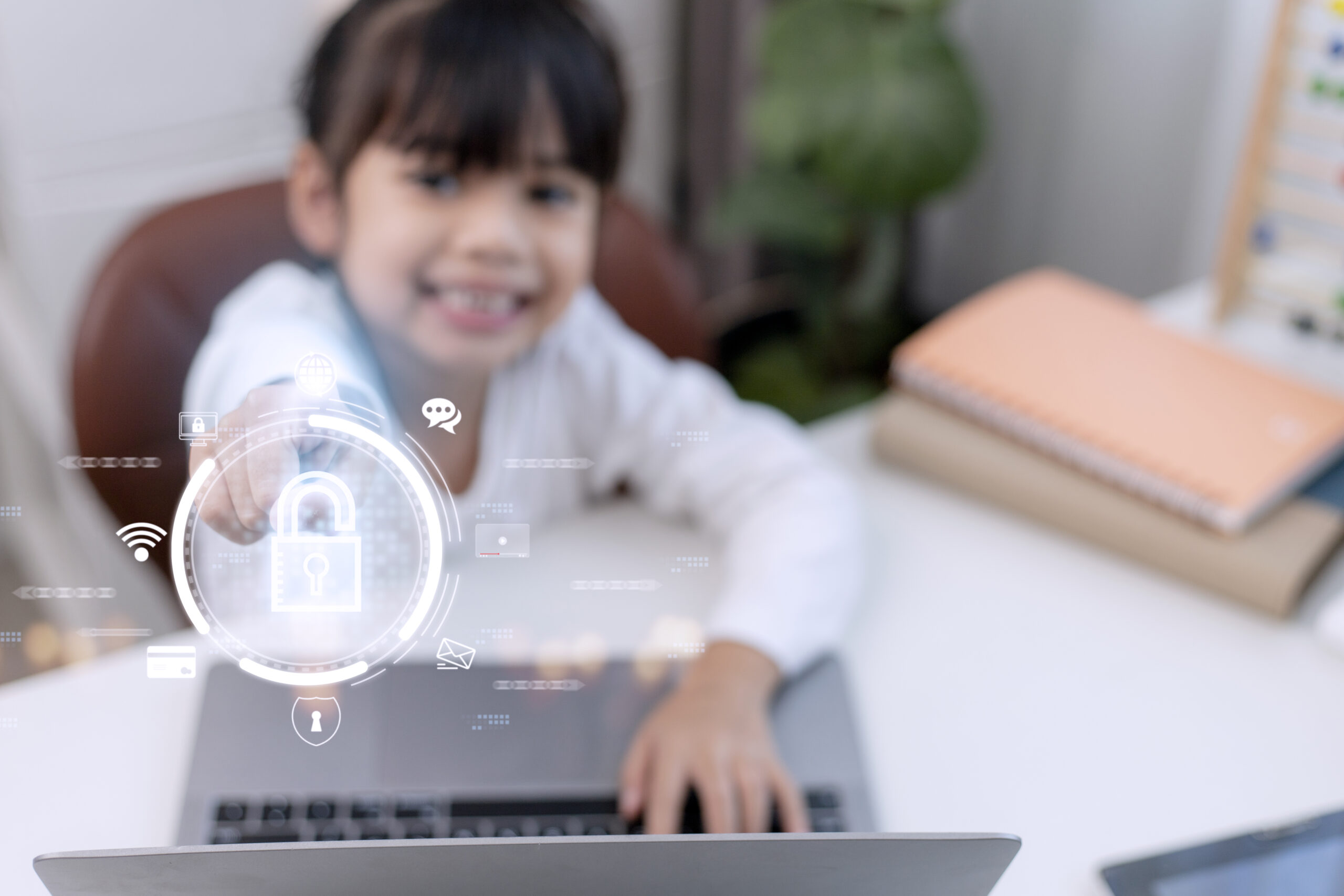 Child safety online. Little girl using laptop at home. icon of internet blocking app on foreground